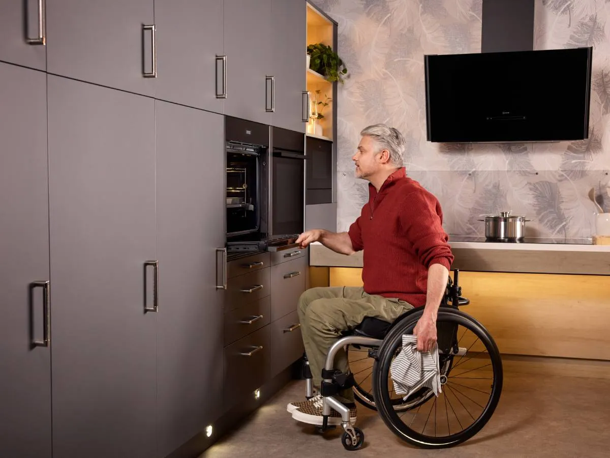 A wheelchair user effortlessly opens the door of a built-in Slide & Hide oven. For easy access, it’s installed low and the door fully retracts