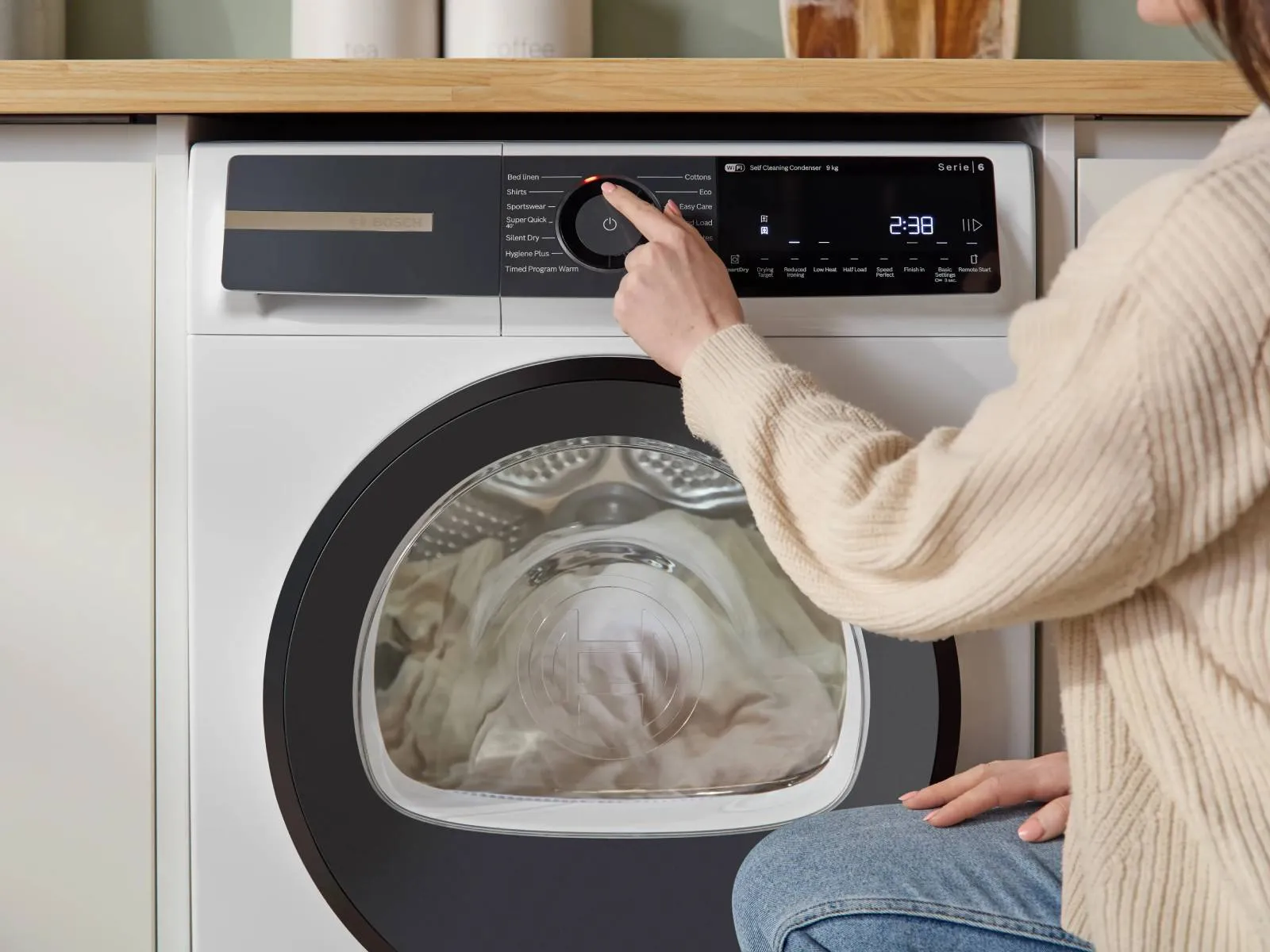 Person using display panel on tumble dryer