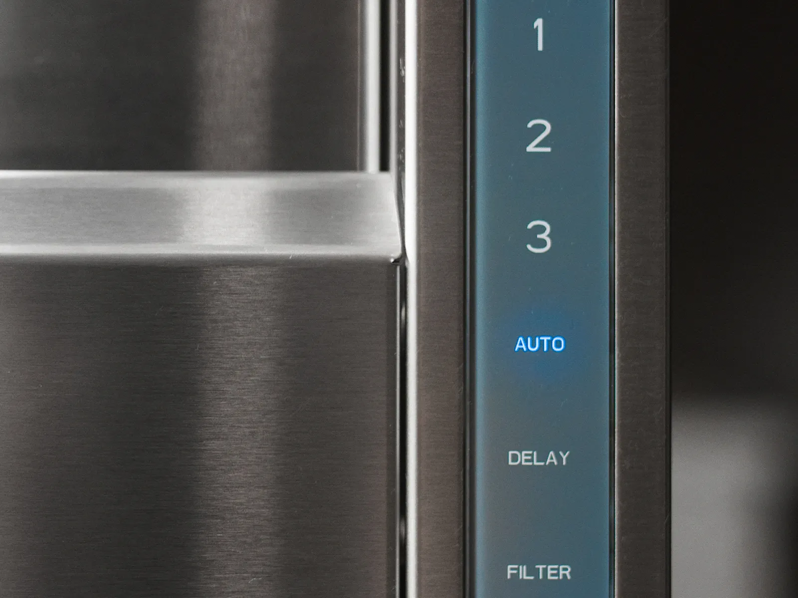 Close-up of a stainless steel telescopic downdraft ventilation system control panel showing fan speed levels and auto mode active.