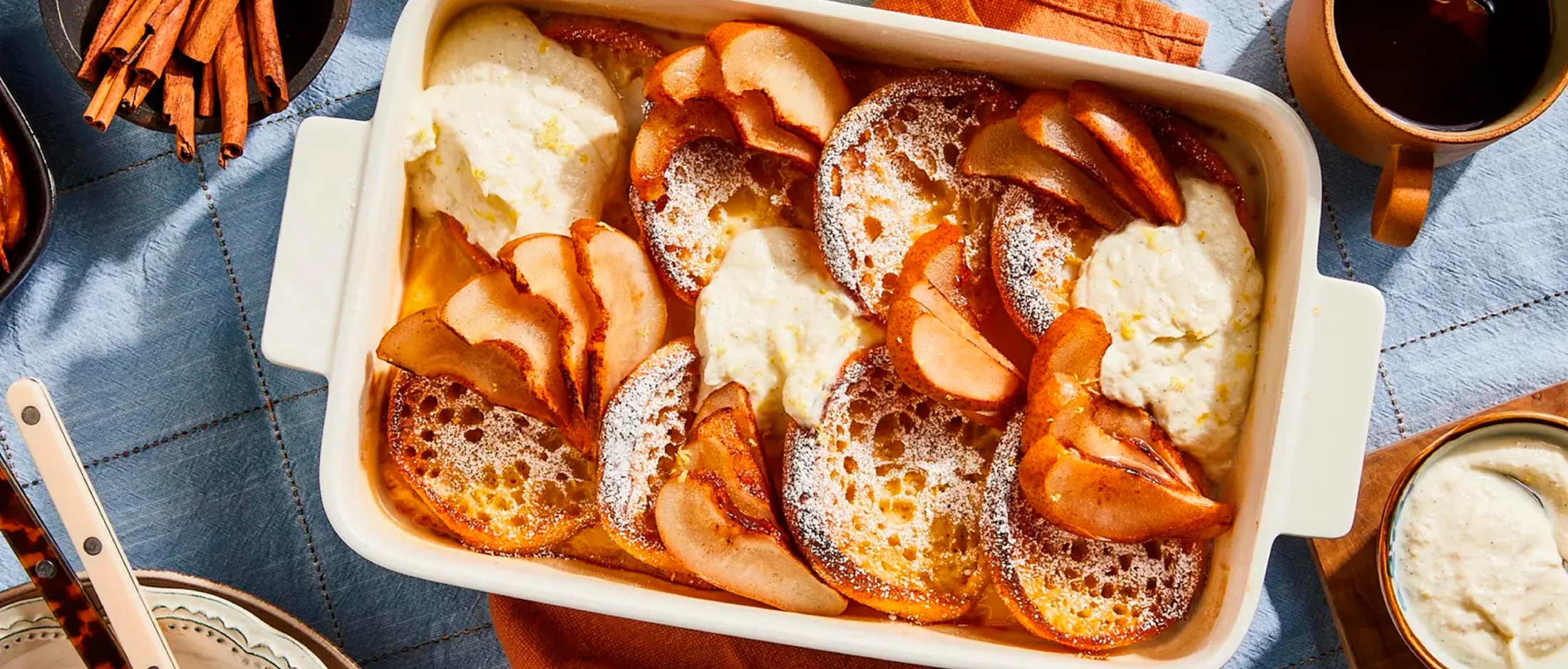 Baked apple slices with cinnamon and sugar in a white baking dish, surrounded by orange napkins and utensils.