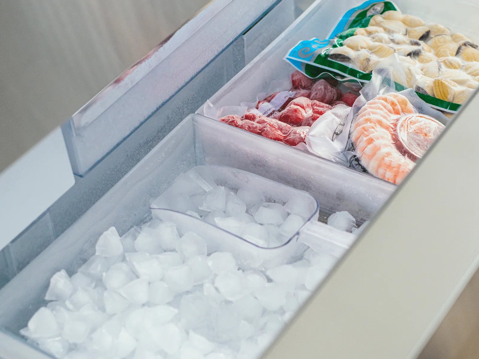 Freezer drawer filled with ice and frozen seafood showing organized storage compartments