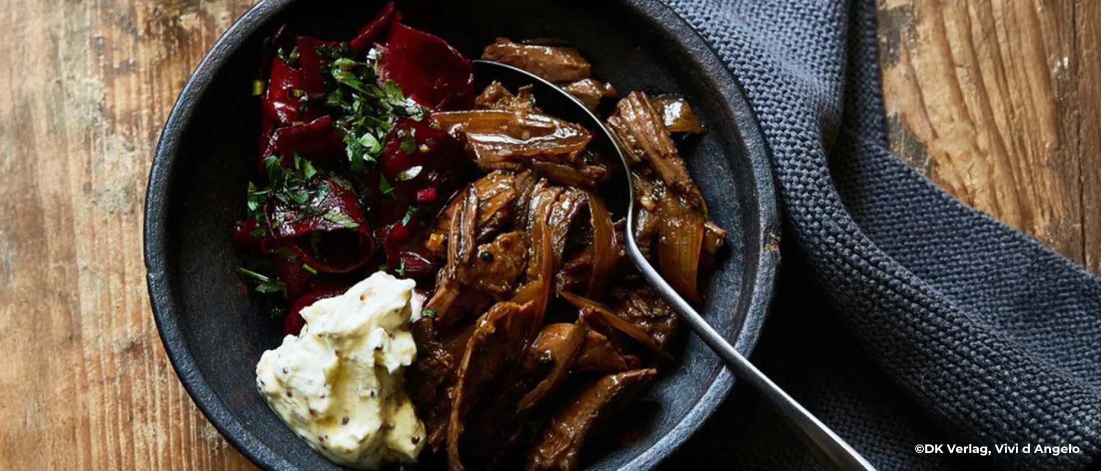 Pulled Wildschwein mit Rote-Bete-Salat und Dip angerichtet in einem dunklen Teller.