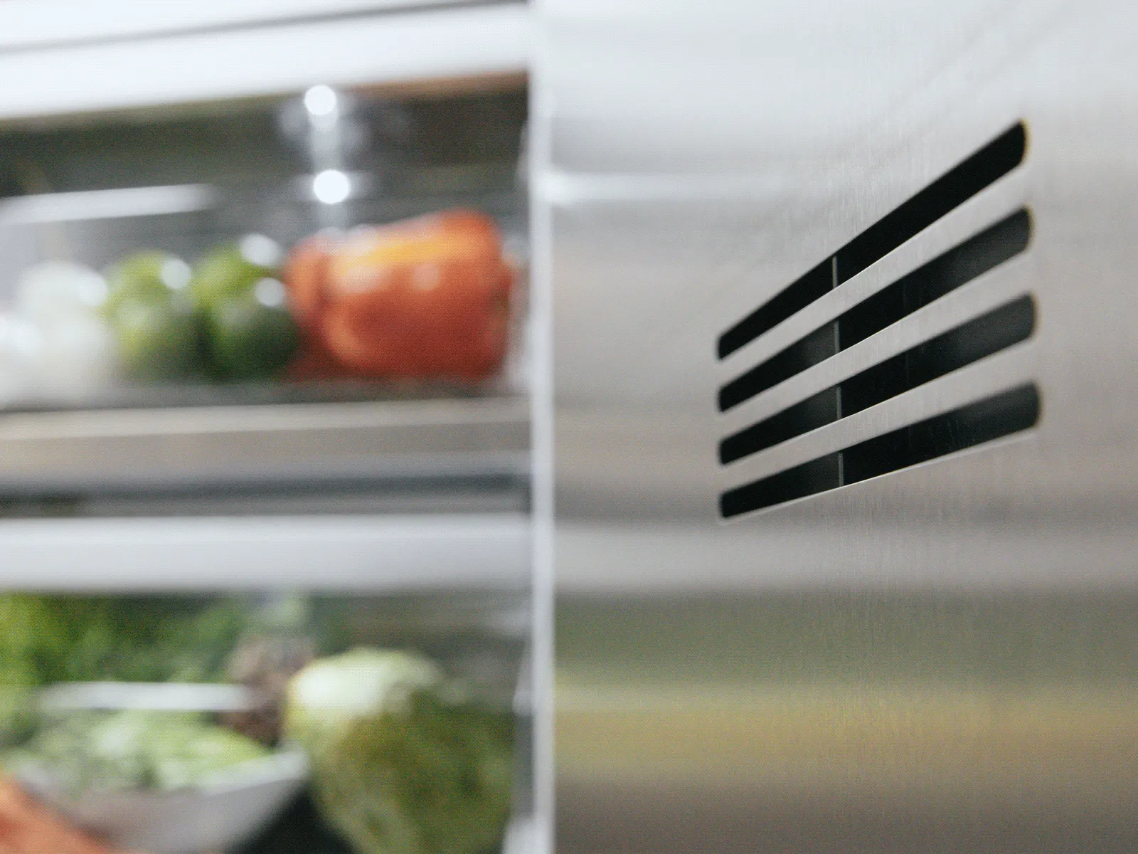 Open refrigerator door showing fresh vegetables and eggs on shelves inside a stainless steel fridge.