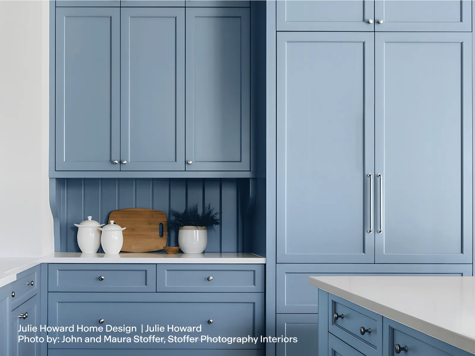Kitchen with dusty blue shaker cabinets and a fully integrated panel-ready refrigerator.