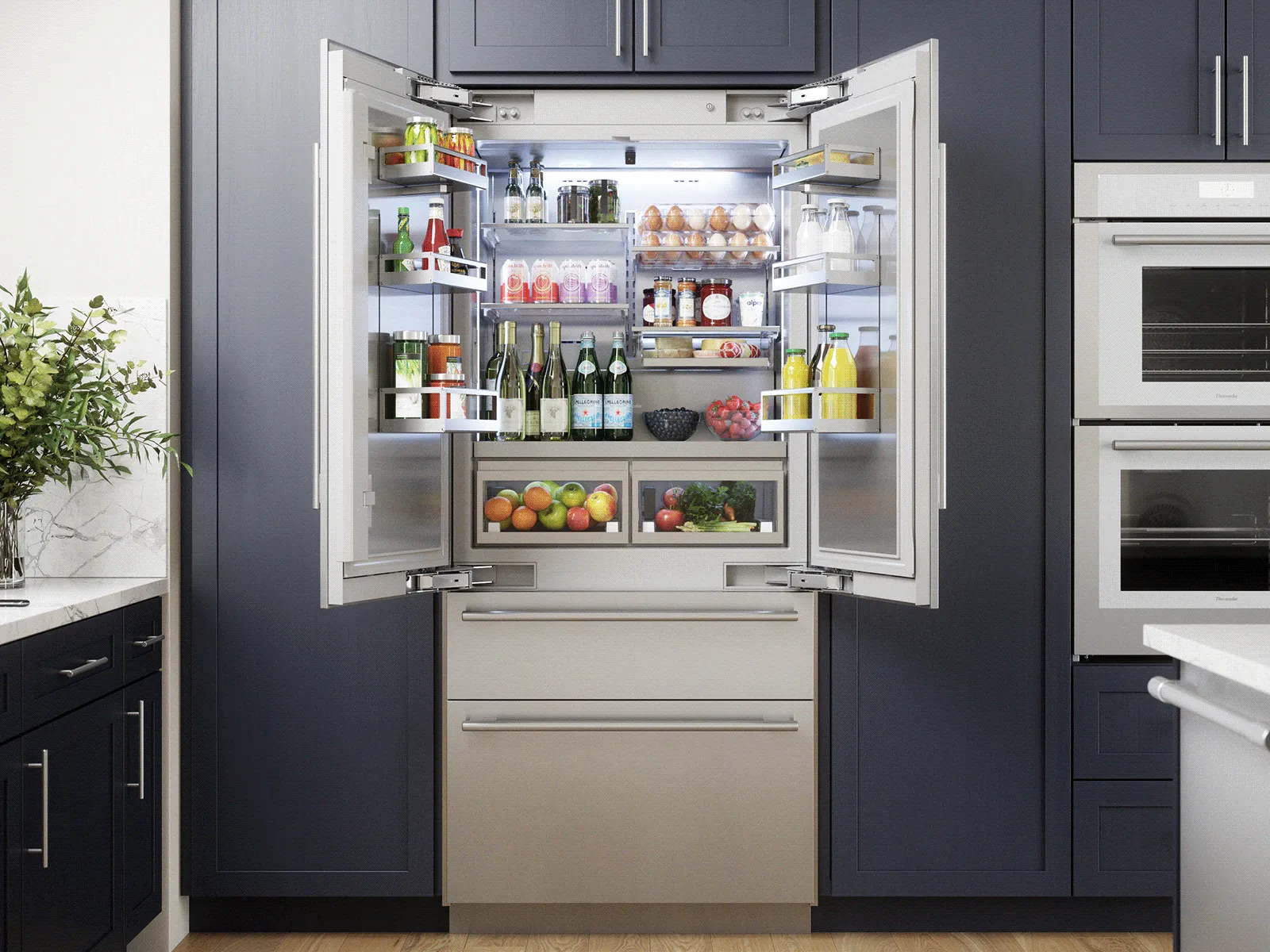 Open French door refrigerator stocked with food and wine, set in dark blue kitchen cabinets.