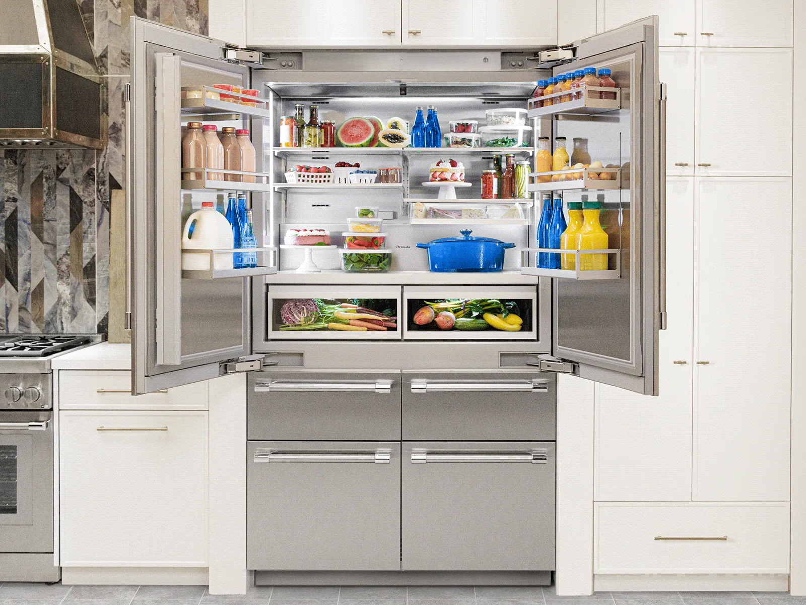 Open French door refrigerator with four freezer drawers, stocked with fresh food in a kitchen.