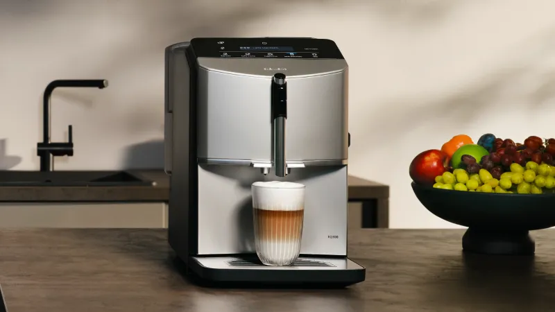 Siemens EQ300 fully automatic espresso machine brewing an latte macchiato on a dark kitchen counter.