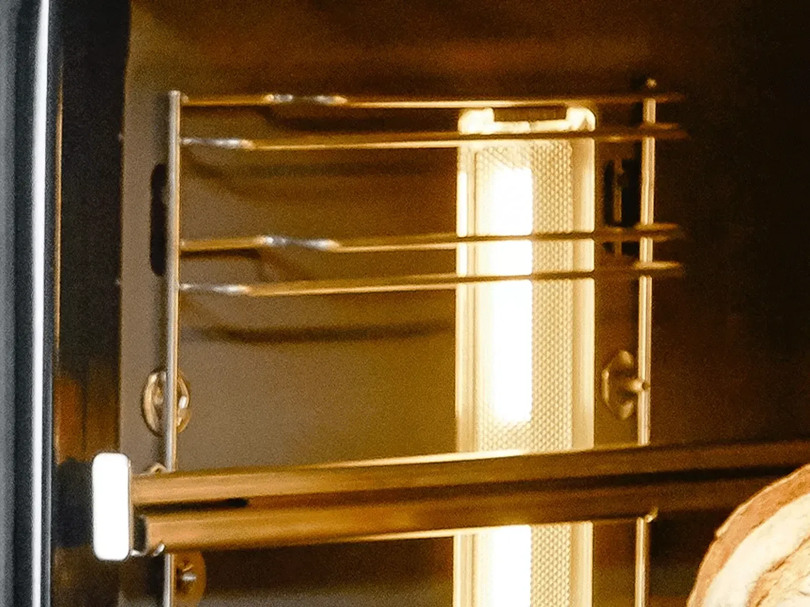 Interior view of an oven with metal racks and a bright internal light illuminating the space.
