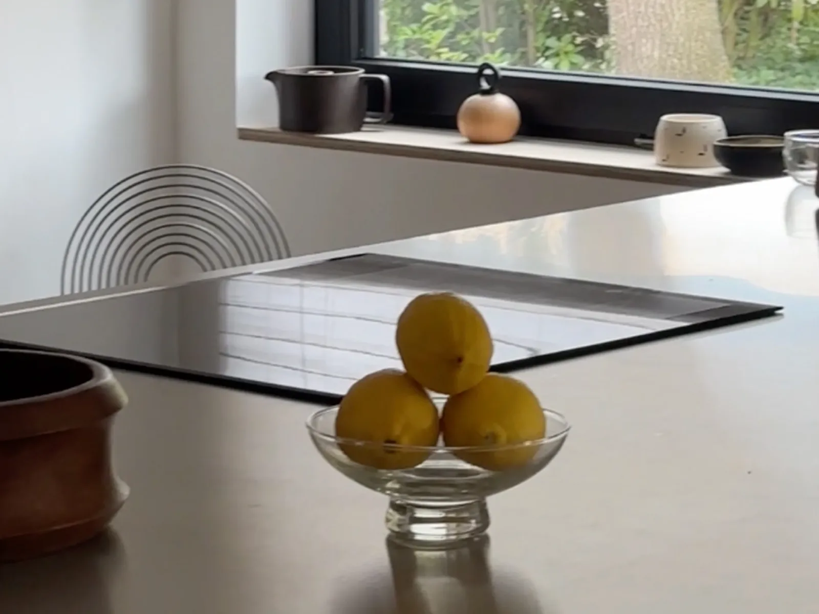 A modern kitchen with a sleek countertop, an induction hob, and a bowl of lemons in the foreground.