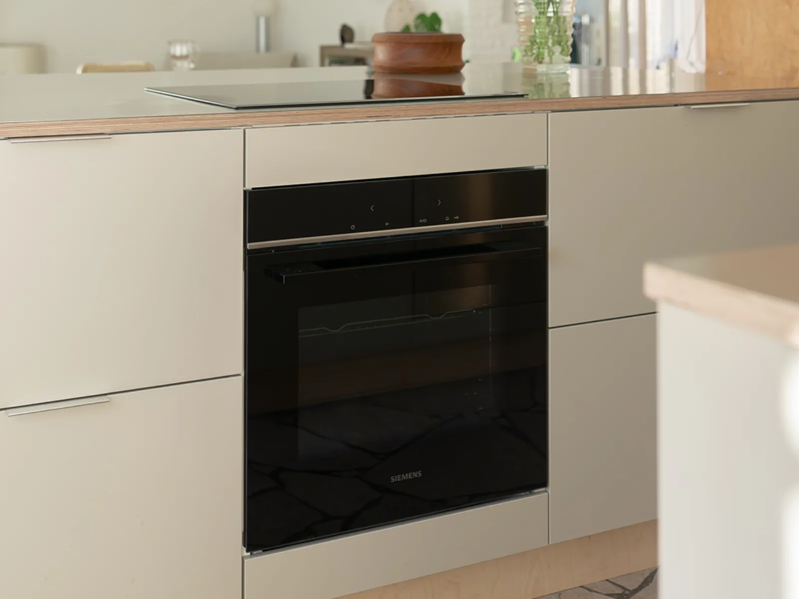 A modern Siemens oven integrated into light-colored kitchen cabinetry with a countertop and induction hob above.