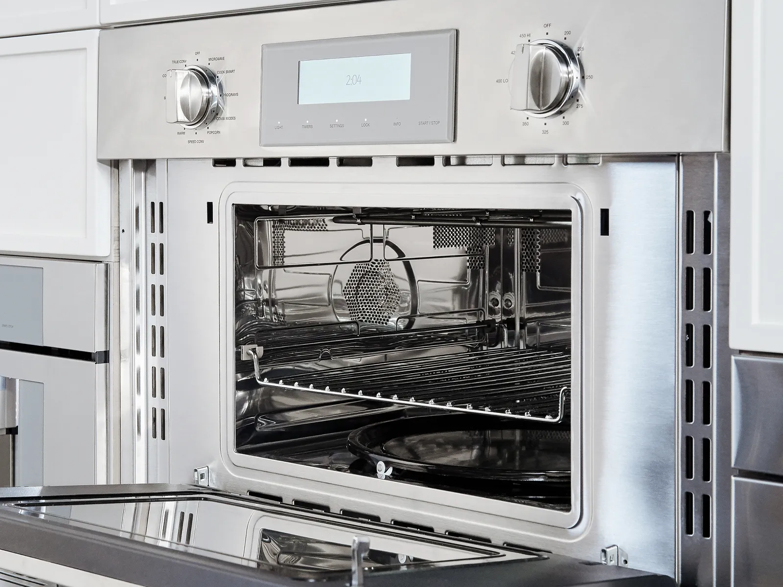 Open stainless steel built-in oven with digital display and control knobs.