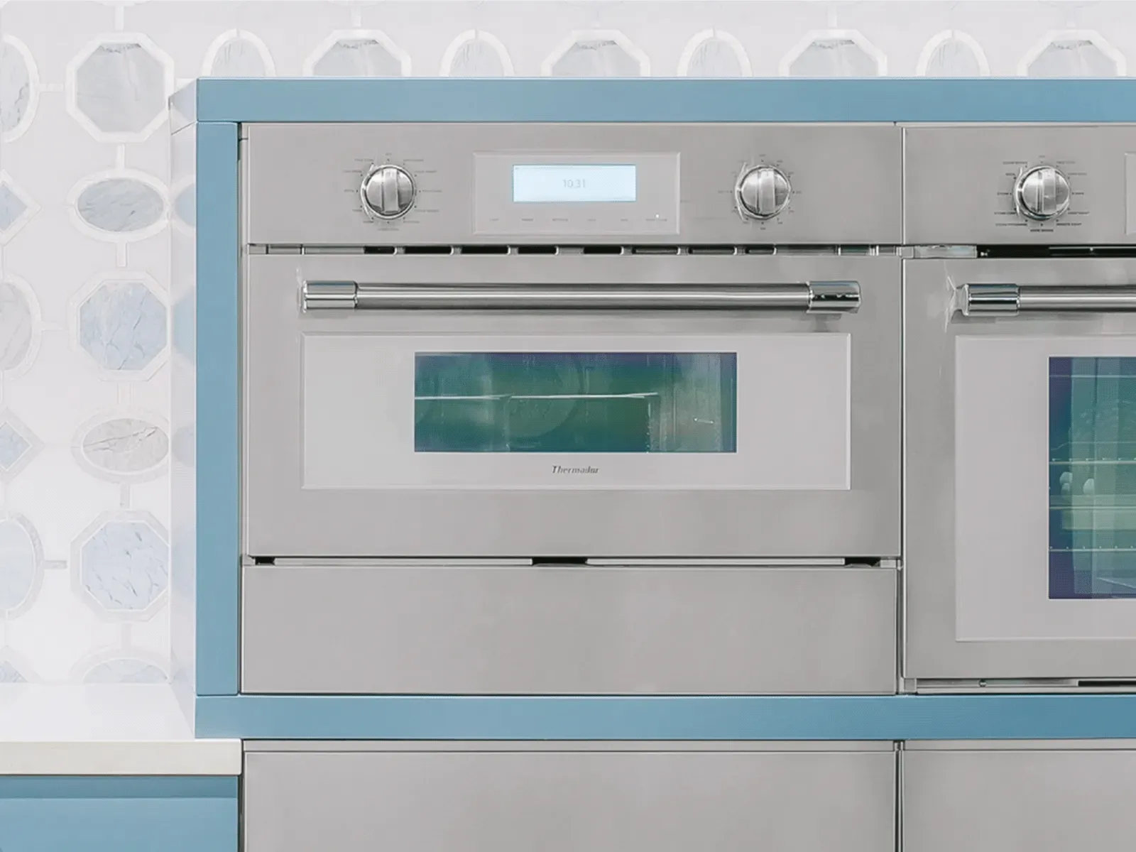 Stainless steel oven with digital display and knobs, set in a blue kitchen decor.