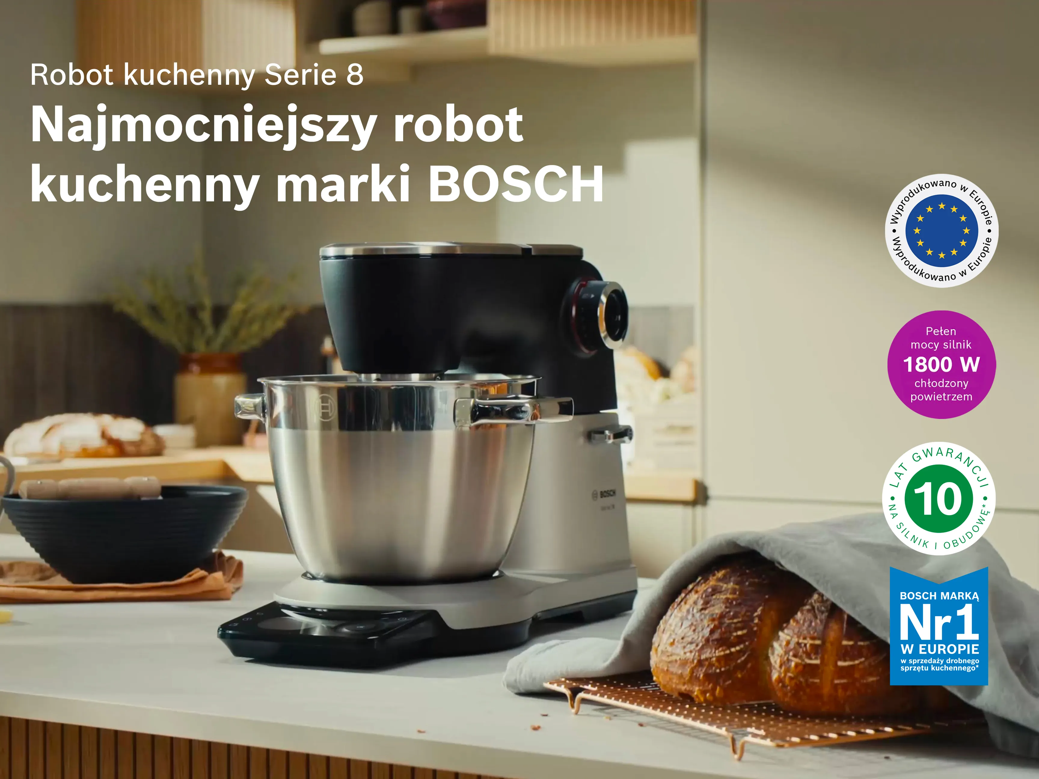 Widok z góry na robot planetarny Serie 8 na blacie stołu, gdy jest w użyciu z hakiem do wyrabiania. Różne wypieki rozłożone na tacy wokół niego.