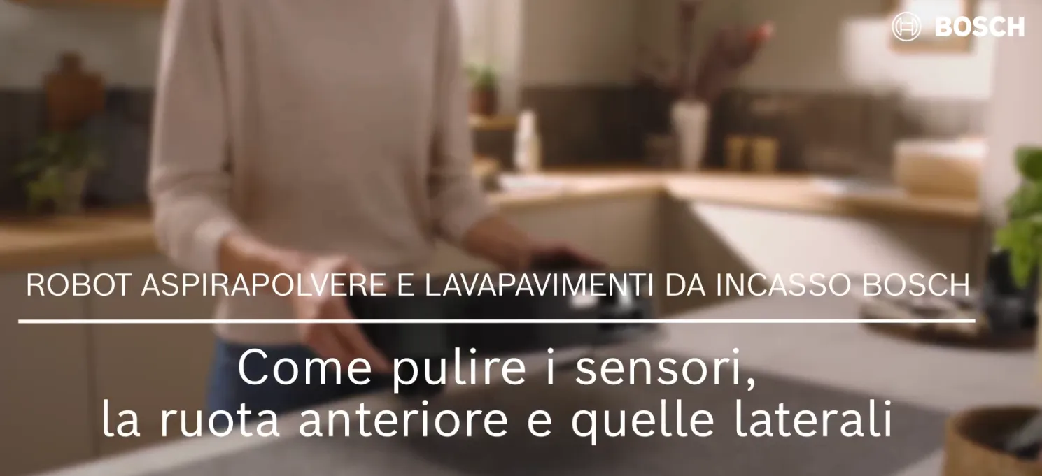 Persona che mostra come pulire i sensori e le ruote di un robot aspirapolvere e per la pulizia dei pavimenti integrato Bosch in una cucina.