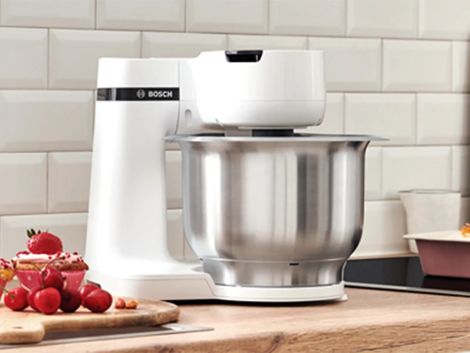 Kitchen appliances, baking tools, and fresh ingredients on a wooden counter.