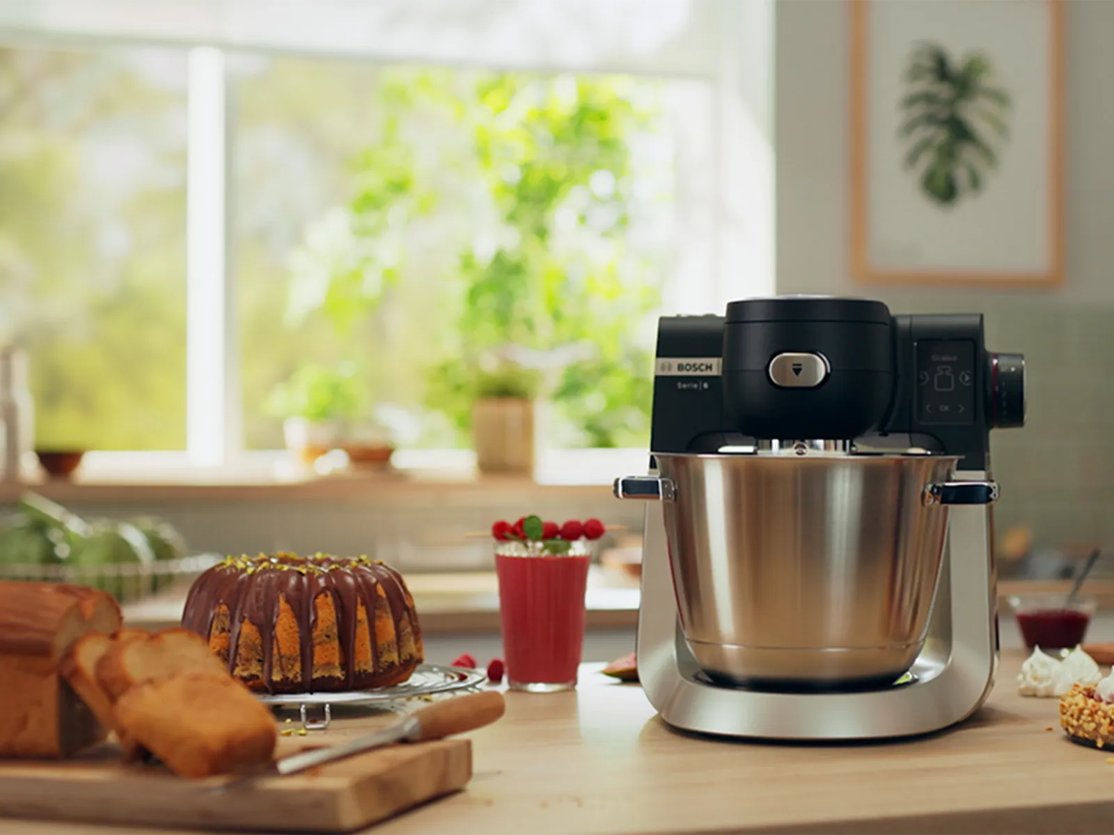 Kitchen counter with baked goods, kitchen appliance, and plants visible through window.