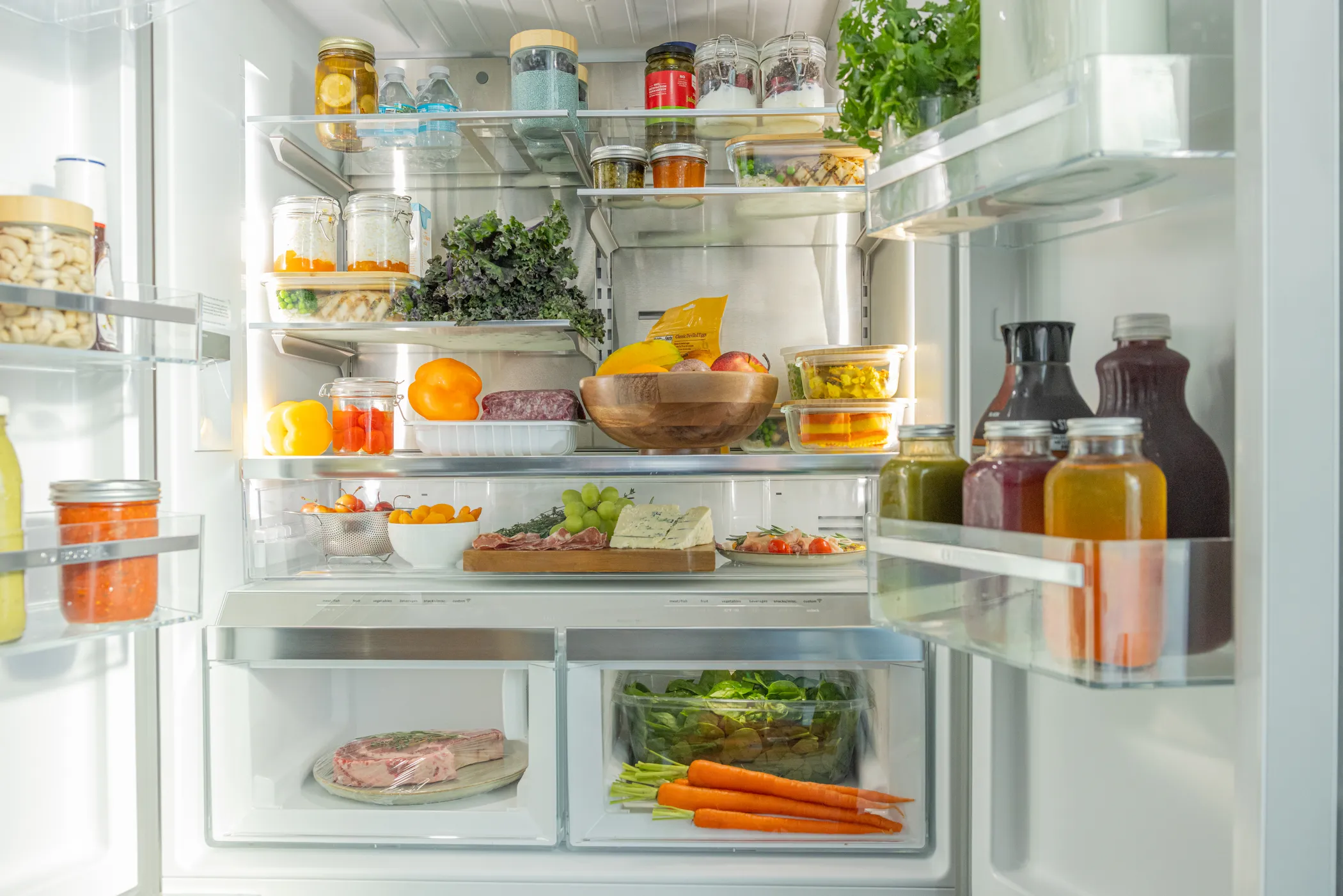 Bosch stainless steel refrigerator open filled with groceries and producess