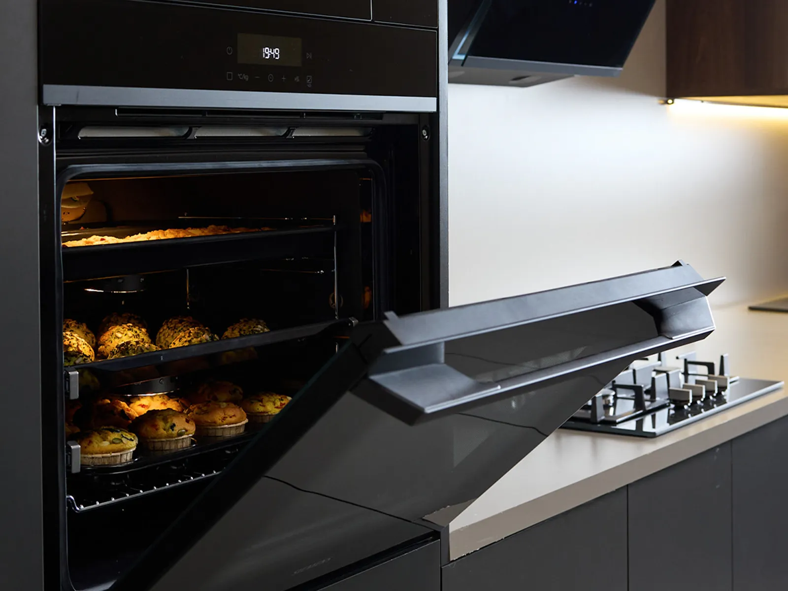 Siemens oven with an open door, revealing delicious muffins baking to perfection in a modern kitchen. Efficiency meets style.