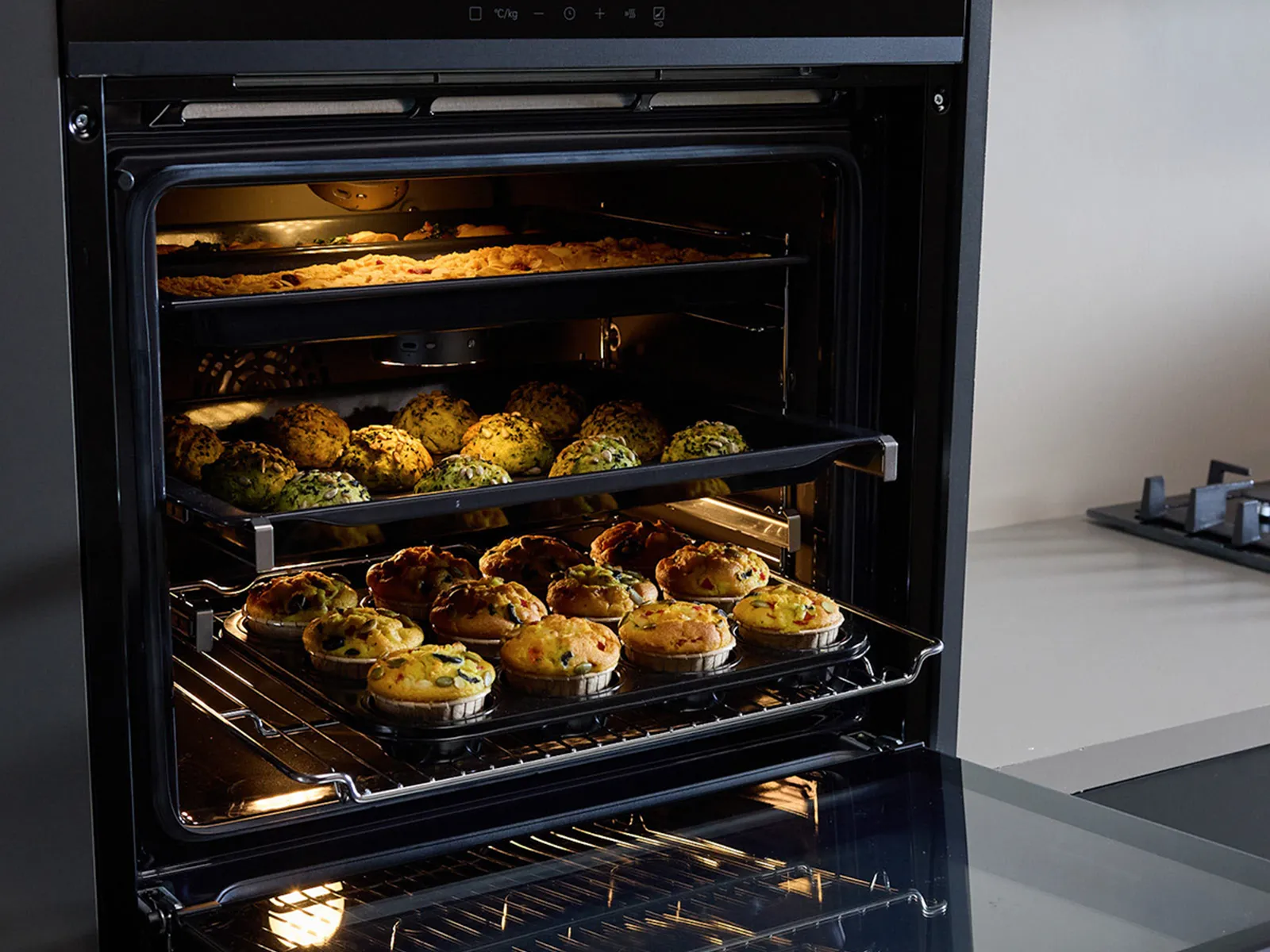 Siemens oven filled with a variety of colorful muffins and cookies, showcasing culinary creativity in a modern kitchen.