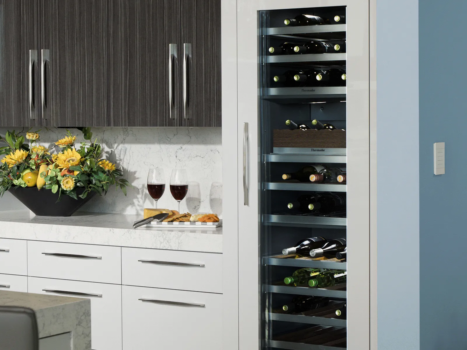 Tall, narrow built-in wine refrigerator with a glass door and interior lighting displaying horizontal bottles