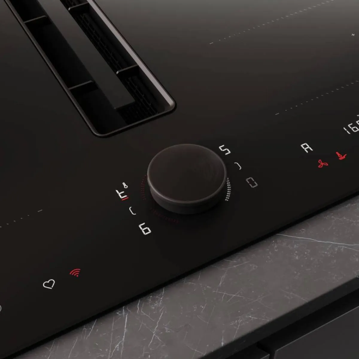 A finger adjusts the illuminated red digital control dial of a black induction cooktop, showing various settings.