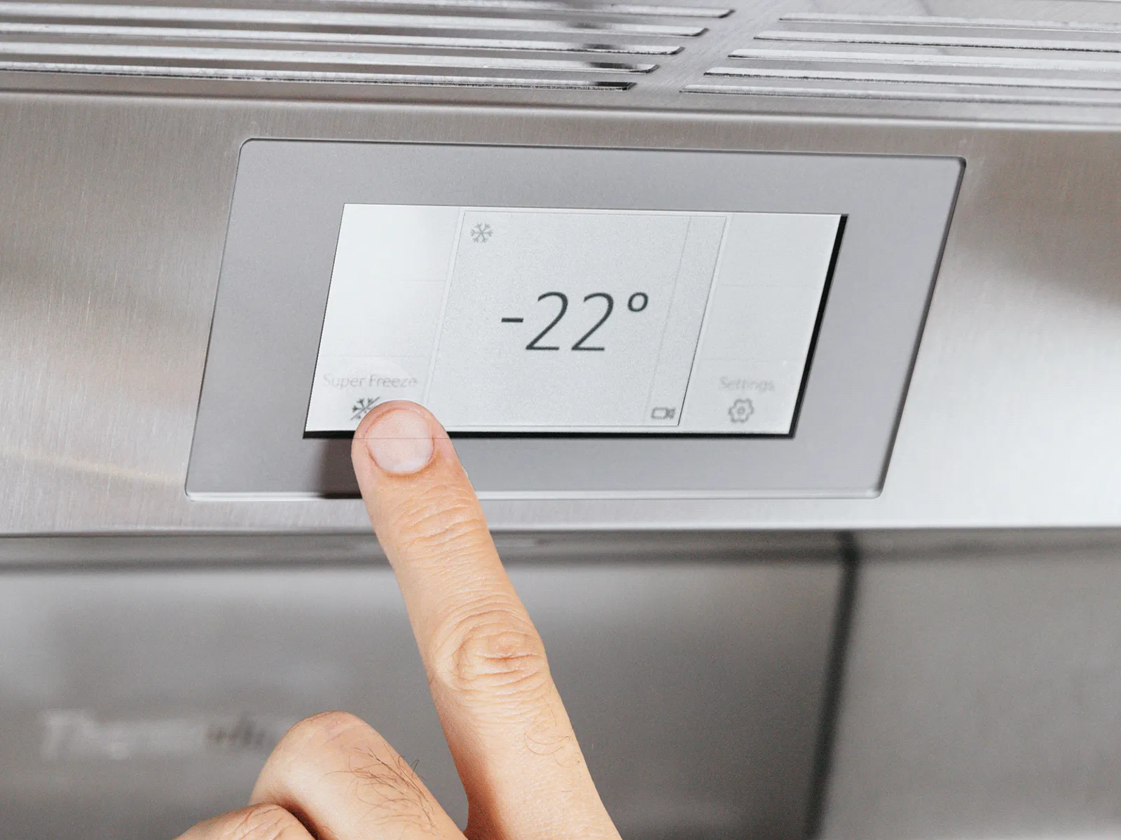 Close-up of a stainless-steel refrigerator touchscreen showing two temperatures—"37°" at the top and "30°" below—with small edit and settings icons in the lower corners.