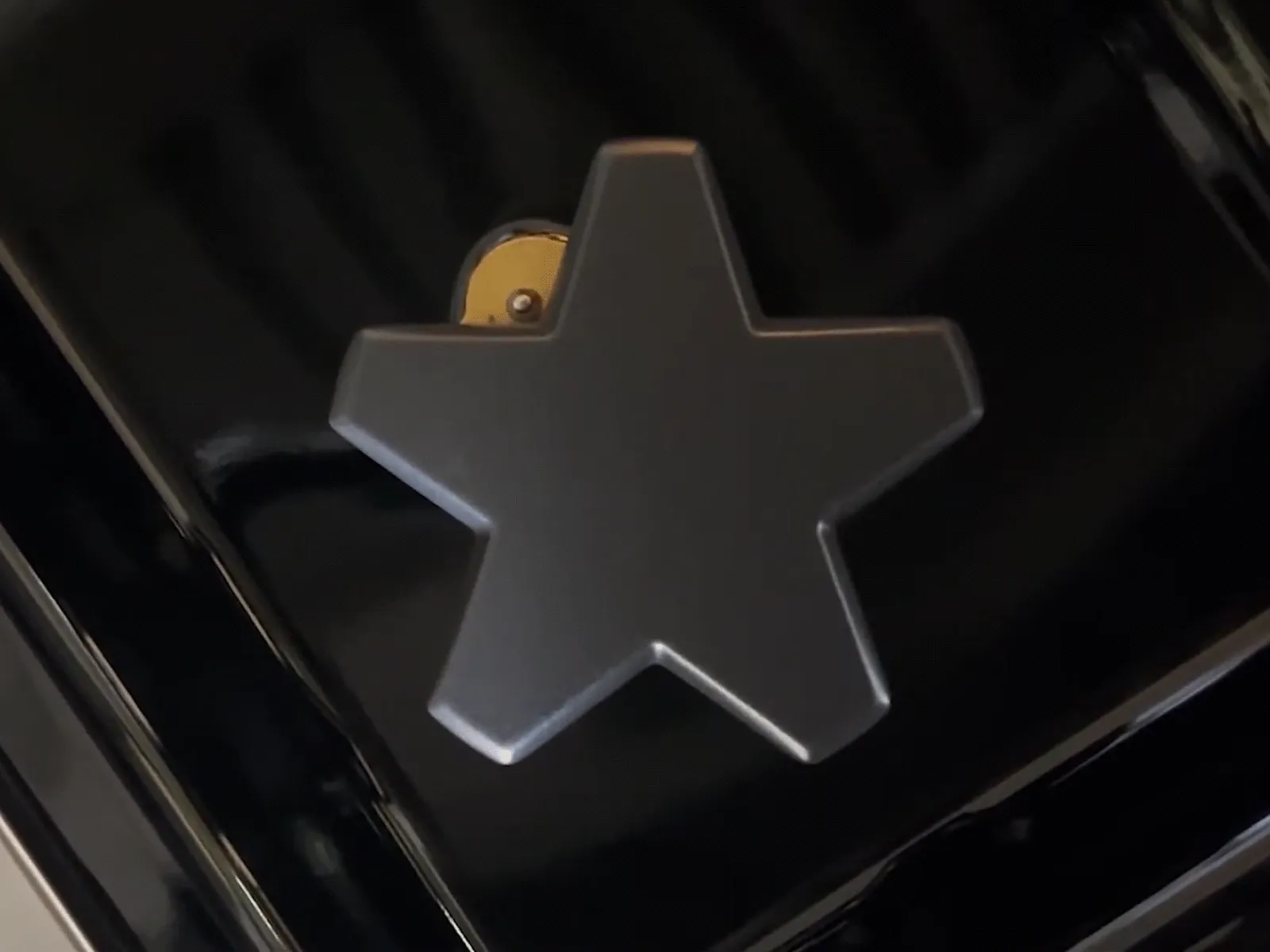 Top-down close-up of a star-shaped gas burner cap surrounded by low blue flames on a glossy black stovetop.
