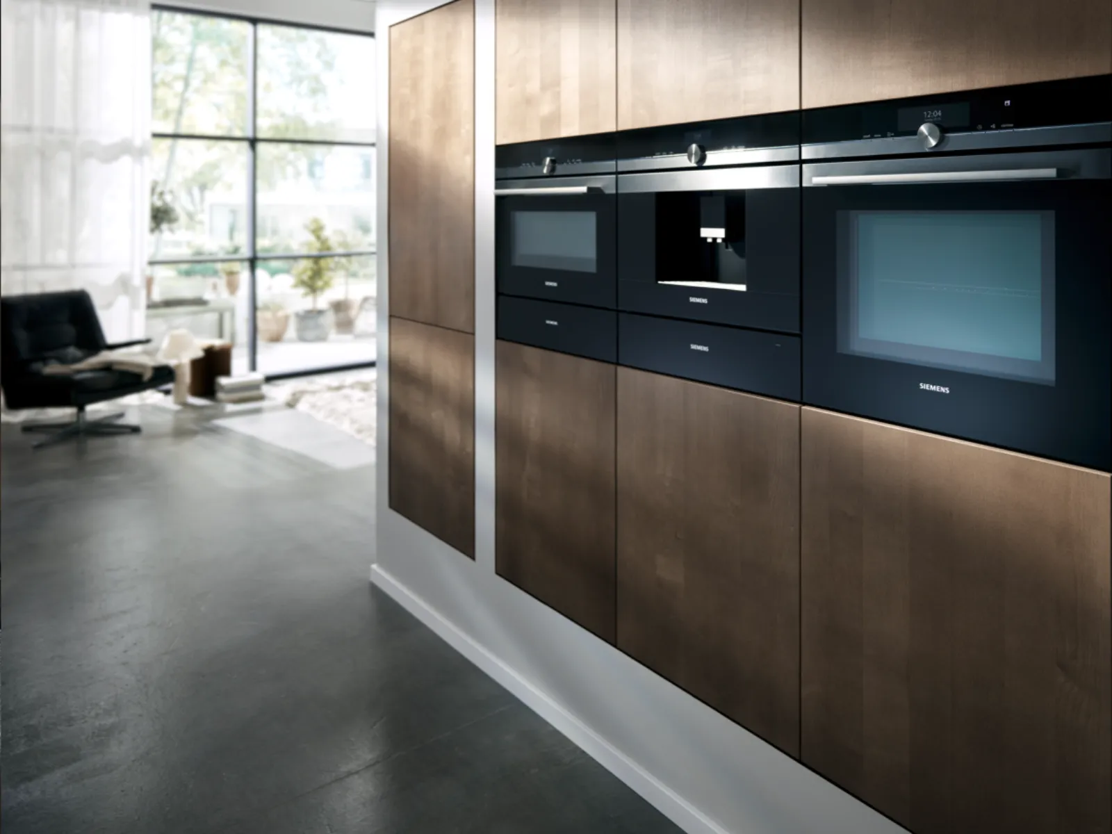 Modern kitchen with sleek black appliances, wooden cabinets, and large window overlooking outdoor scenery.