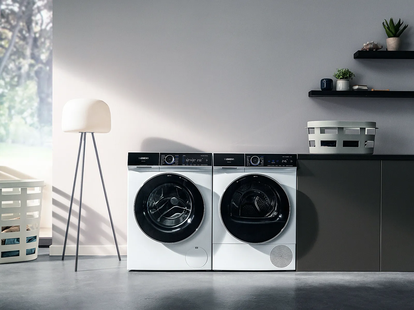 Minimalist laundry room with washing machine, dryer, shelves, and potted plants.