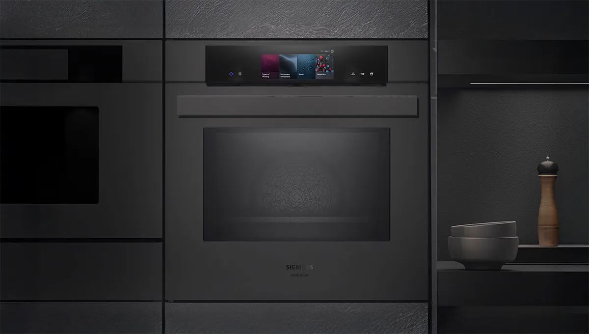 Un elegante forno Siemens di colore nero con un pannello di controllo digitale sulla porta in vetro, perfettamente integrato in una cucina moderna.