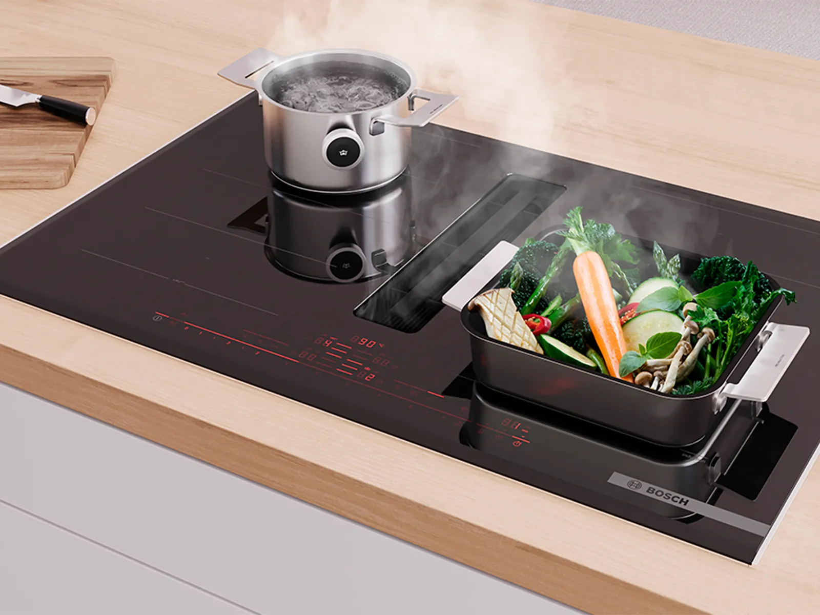 Bosch induction hob with integrated extractor, cooking a boiling pot and steaming vegetables. Red digital controls.