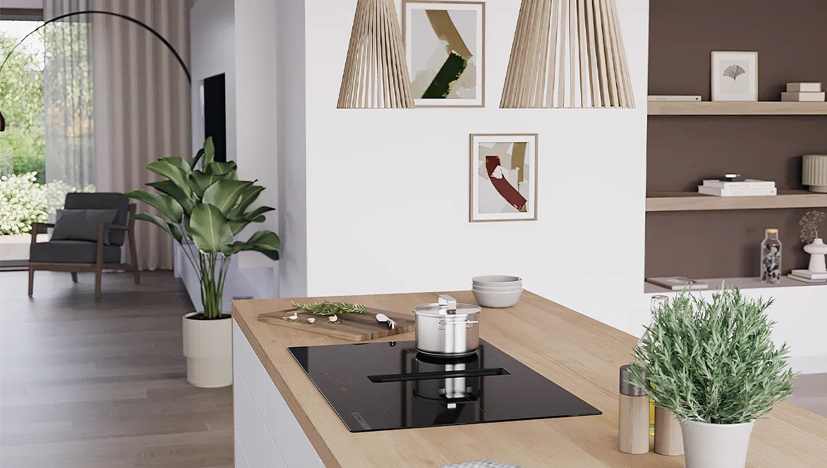 Encimera de inducción Bosch con extractor integrado en una moderna isla de cocina, con una olla, hierbas y una planta. Sala de estar al fondo.