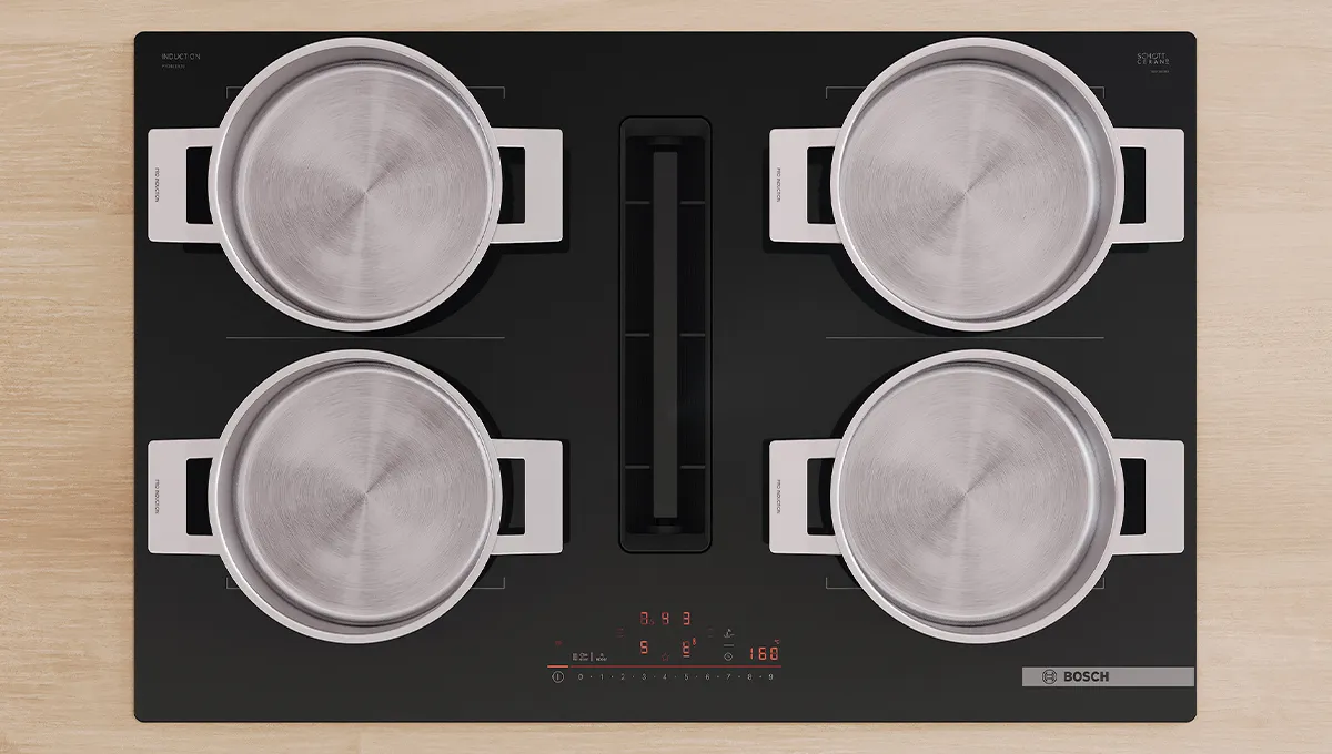 Vista cenital de una encimera de inducción Bosch con extractor integrado, cuatro ollas plateadas cocinando y controles digitales rojos.