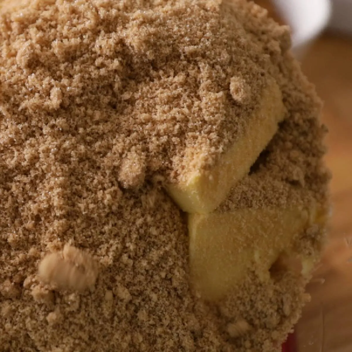 A close-up of a food processor bowl filled with brown sugar and cubes of butter.