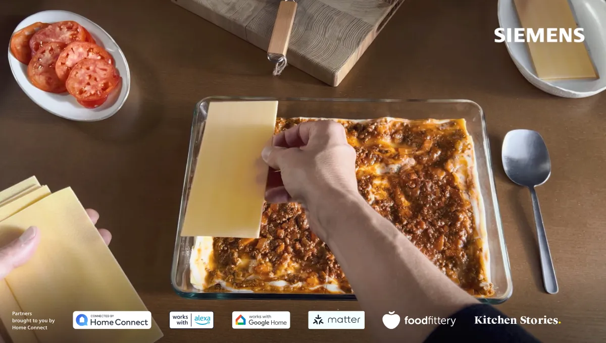 Fetta di pizza con salame piccante, formaggio e salsa di pomodoro su un tavolo in legno con posate.