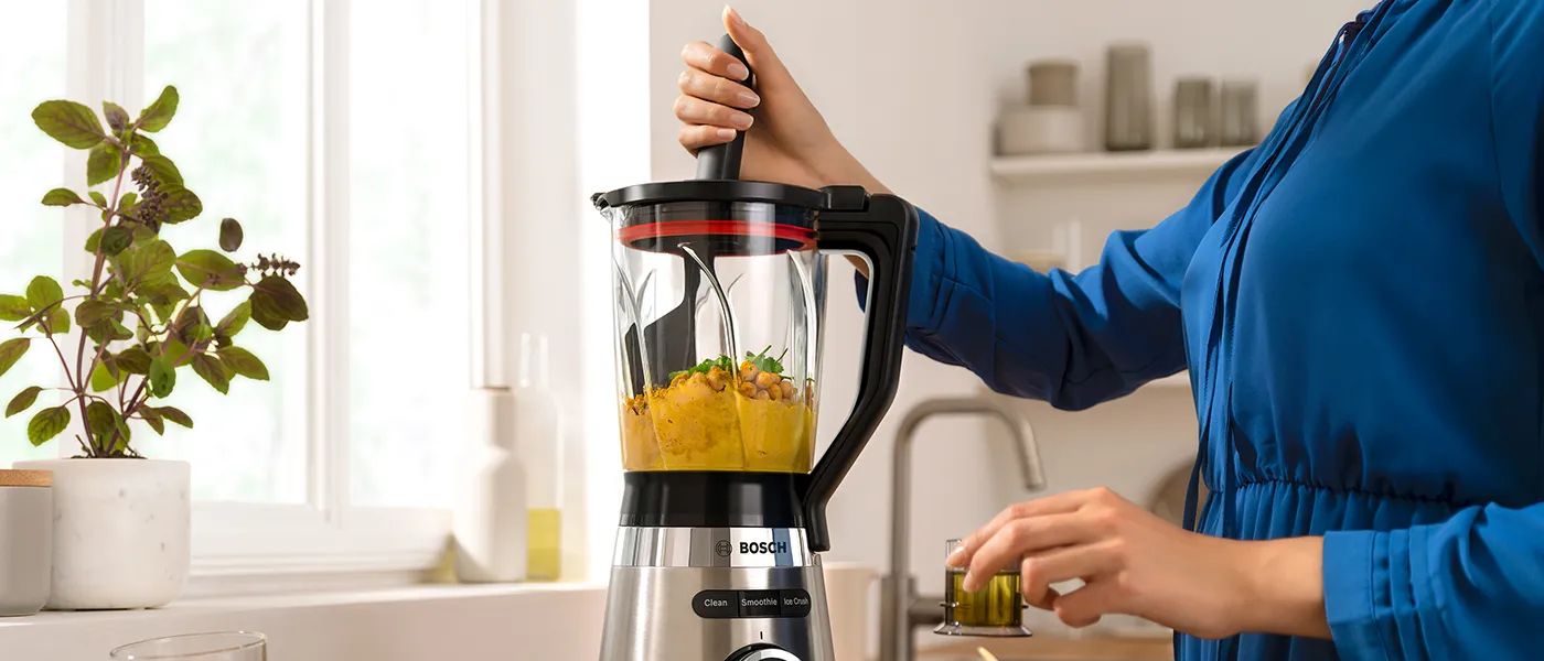 Persona che utilizza lo spintore per frullare i ceci su VitaPower Series 4.