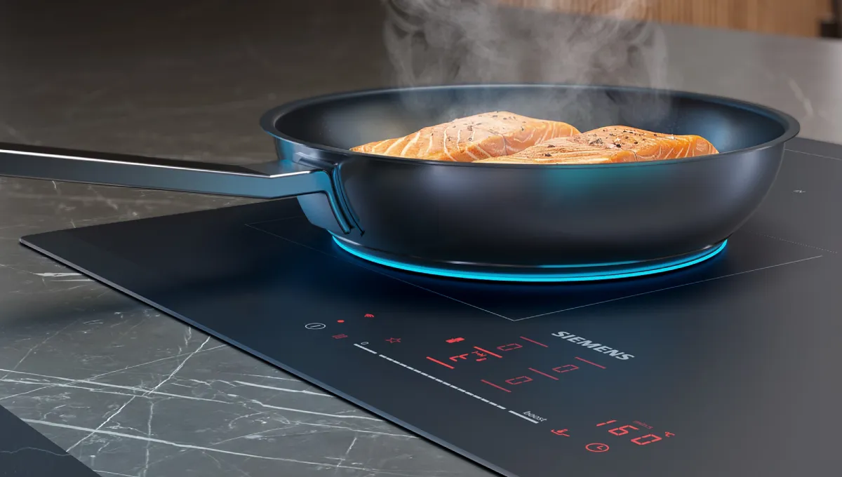 A frying pan with sizzling food sits on a sleek induction cooktop, emitting steam in a modern kitchen setting.