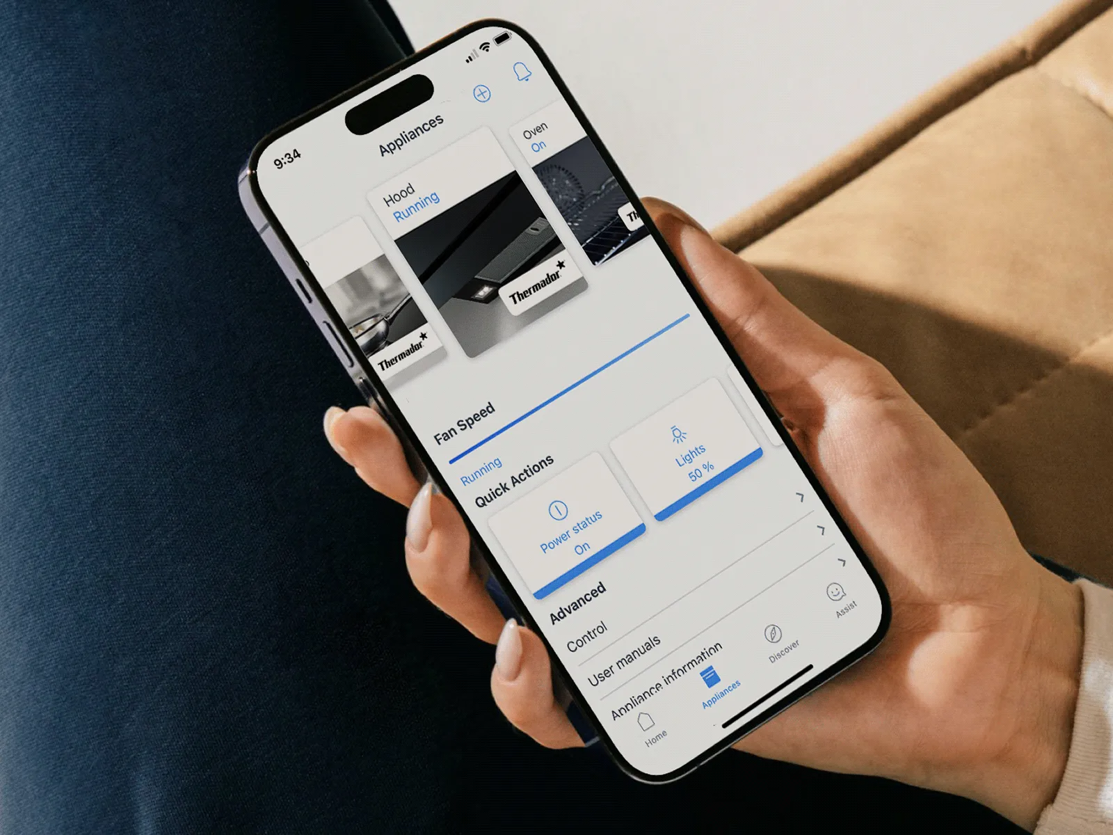 Woman using the Home Connect app on her phone to control a Thermador island hood.