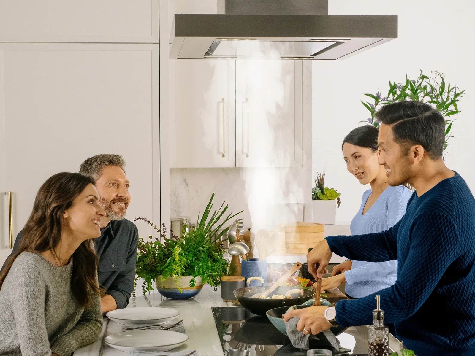 Friends and family cooking together under a 42-inch Thermador Masterpiece island hood.