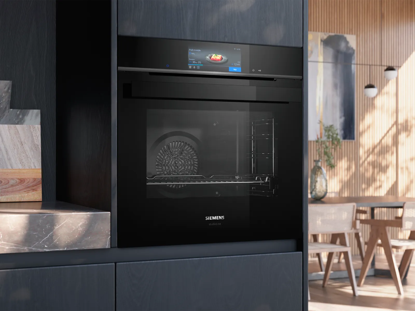 Black Siemens studioLine oven with digital display showing "Fruit crumble" settings in a modern kitchen.