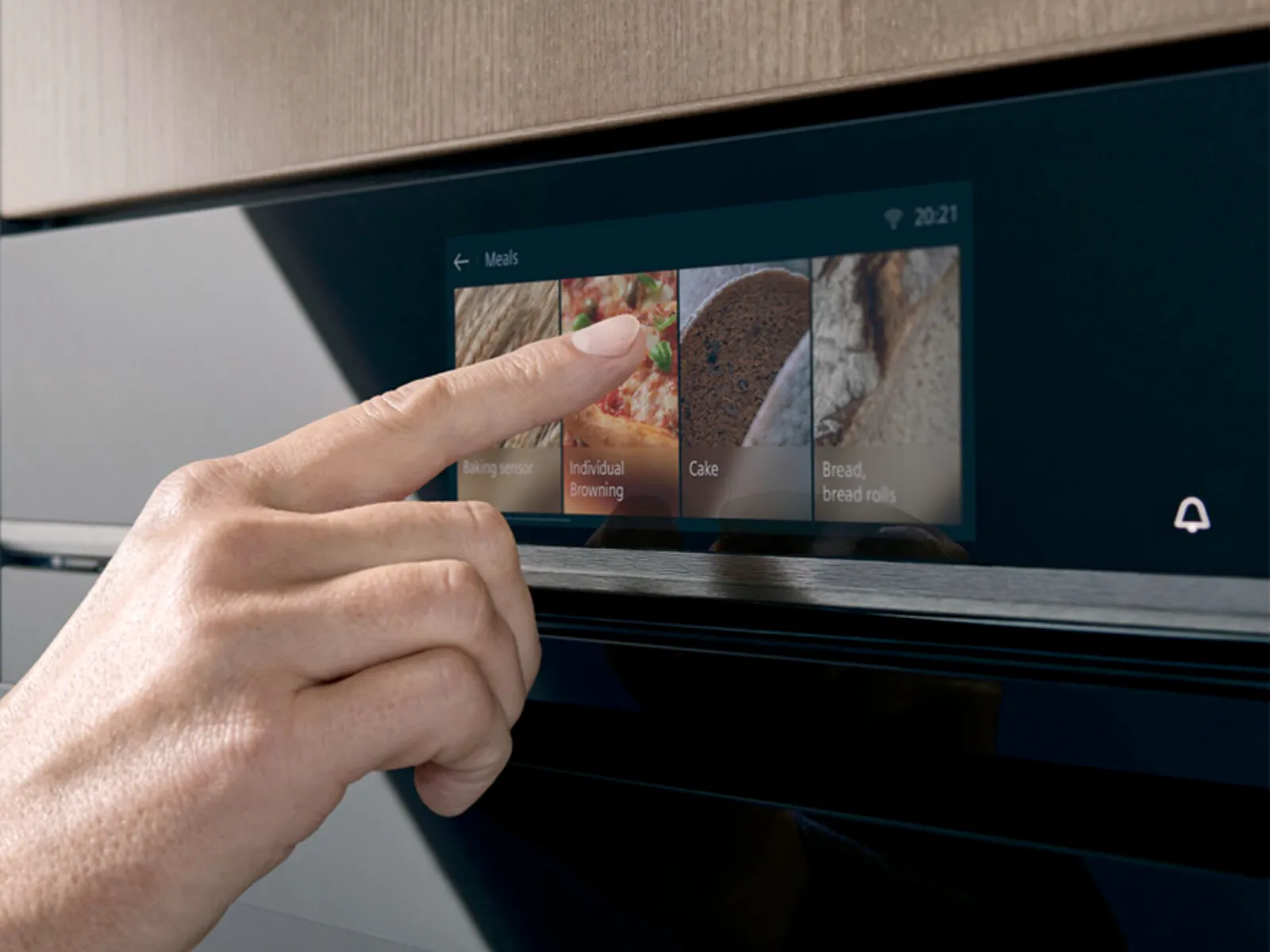 Hand touches Siemens oven's digital display, selecting 'Individual Browning' from a menu of meal options.