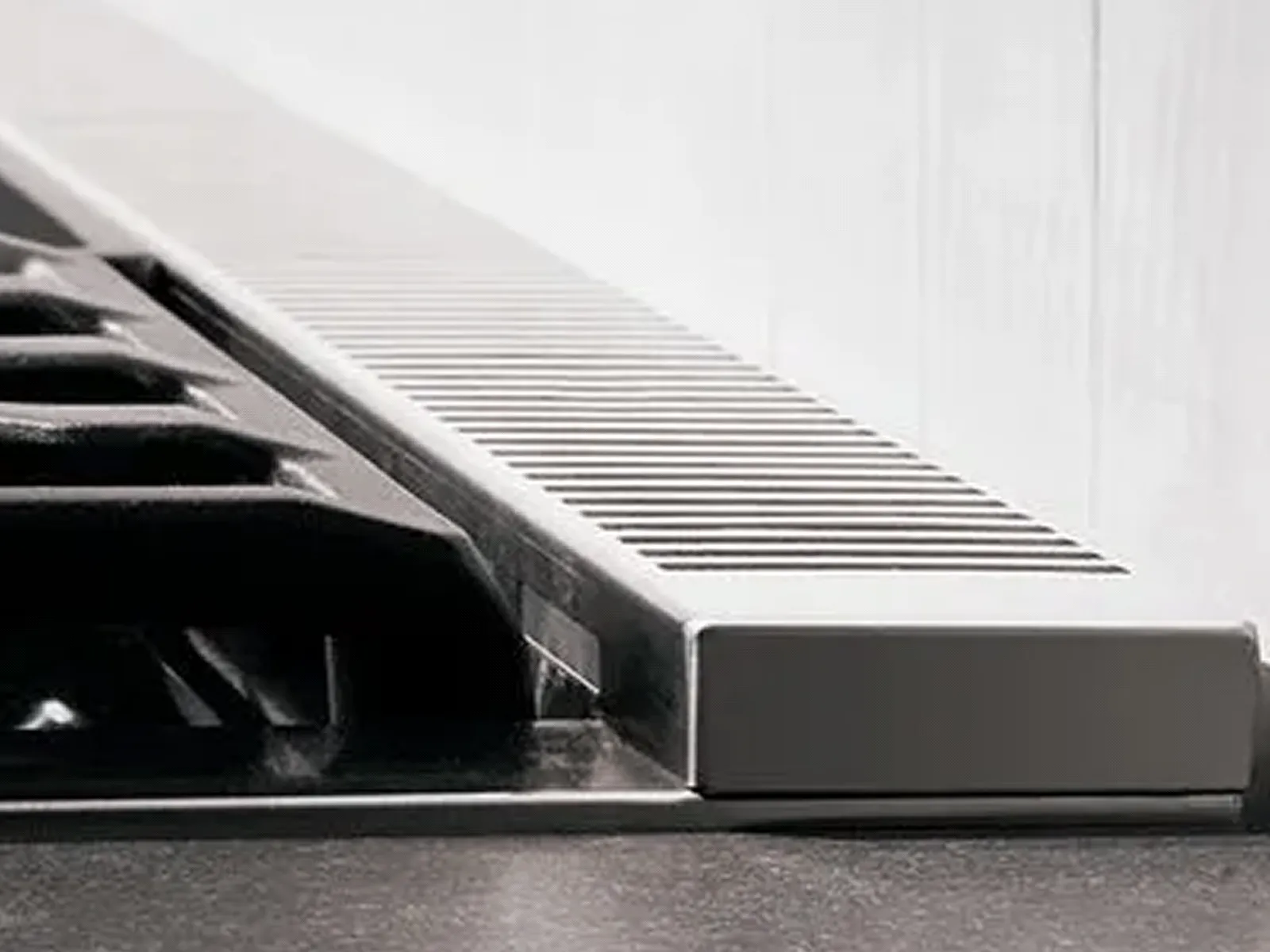 Close-up of a stove's cooktop edge with a slim metal vent grille.