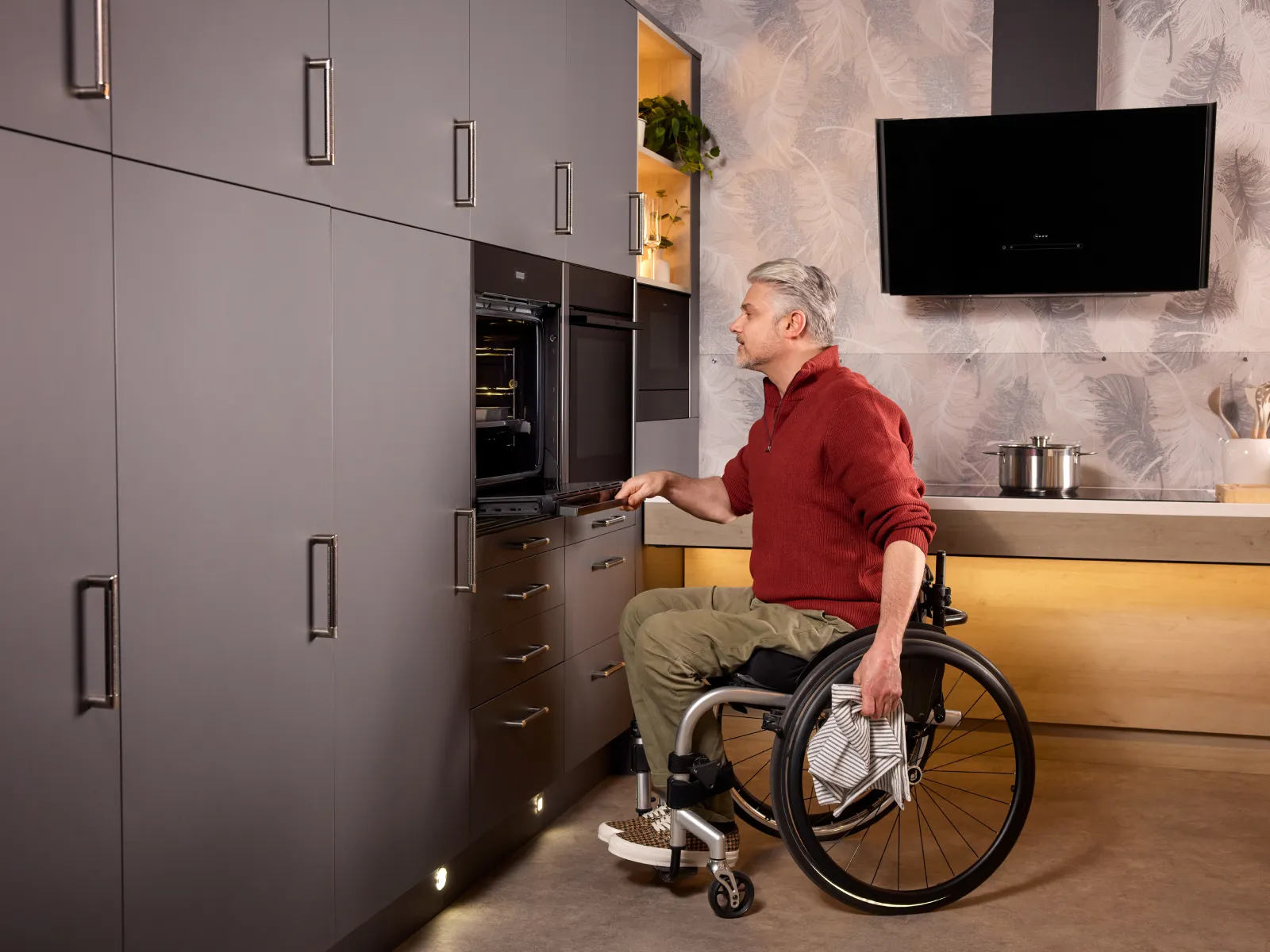 A wheelchair user effortlessly opens the door of a built-in Slide & Hide oven. For easy access, it’s installed low and the door fully retracts.