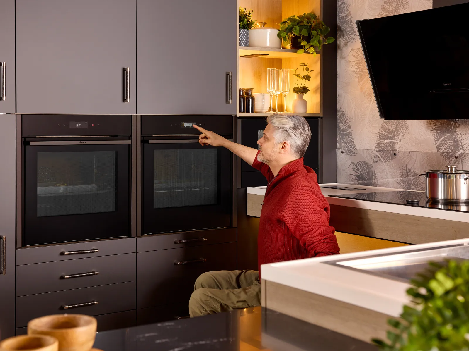 A wheelchair user next to a Slide and Hide oven, touching the TFT oven display to adjust the oven settings.