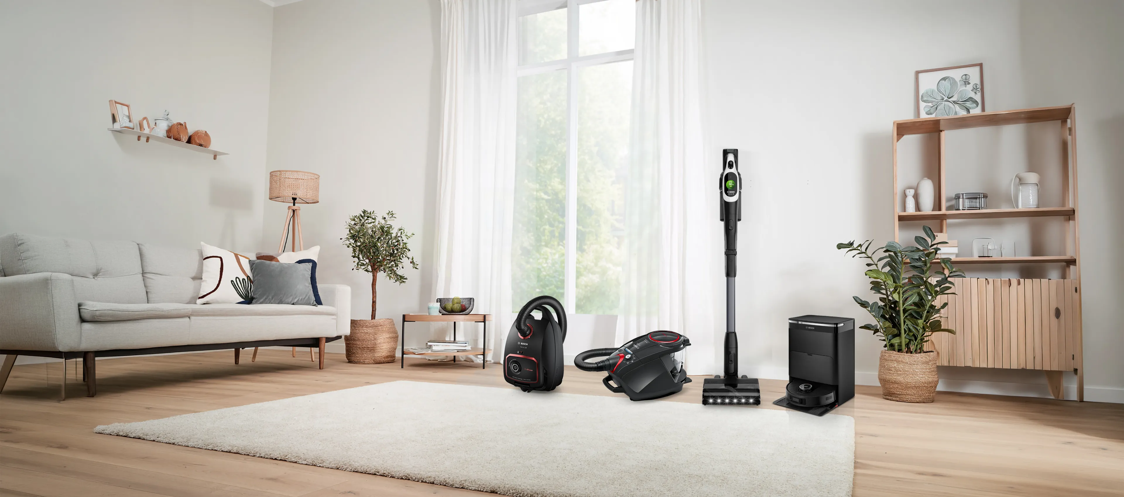 A lineup of four different vacuum cleaners in a bright hallway.