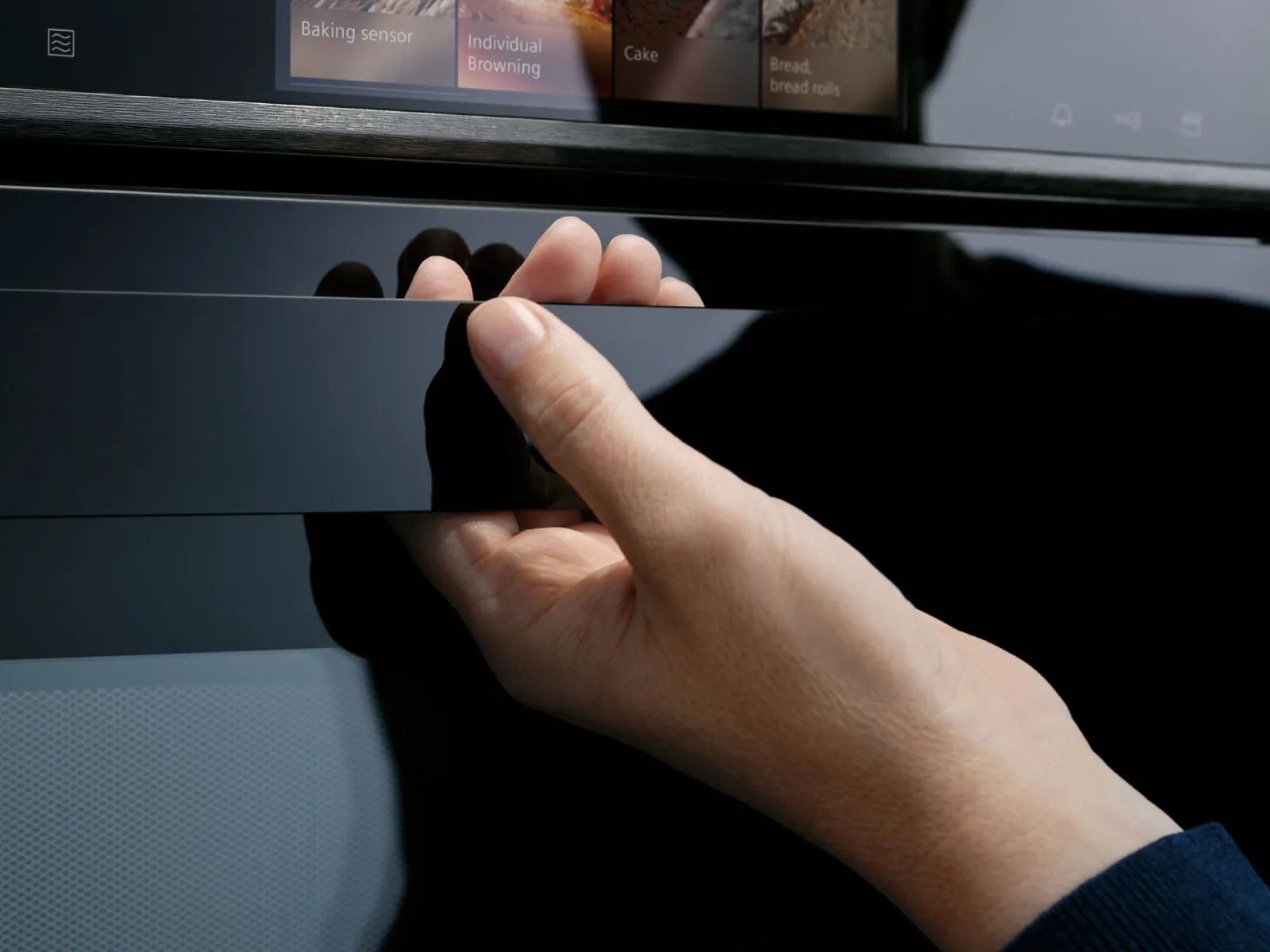 Primo piano di una mano che tiene la maniglia di un forno Siemens iQ700.