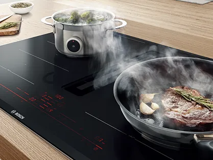 A person holds a smartphone displaying a smart appliance control app, set in a modern kitchen.