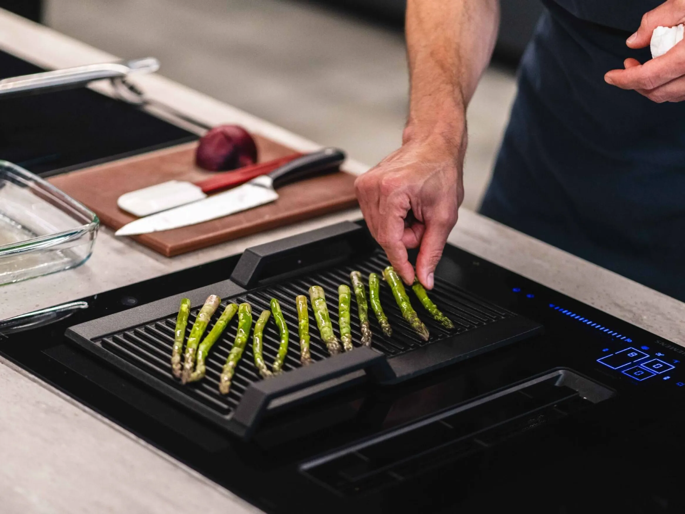 Person laying asparagus on baking tray