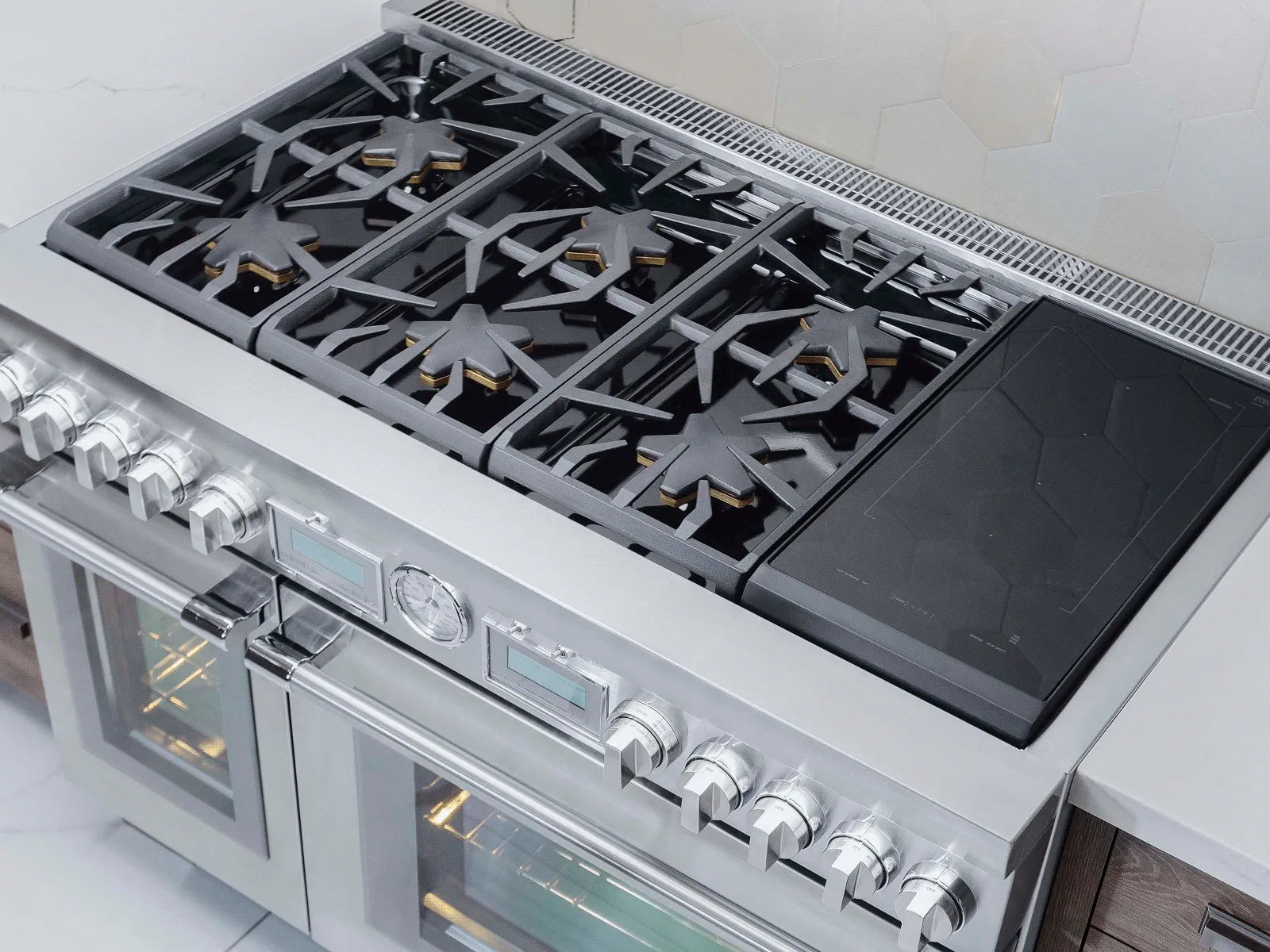 Stainless steel professional gas range with six burners, a griddle, and double oven in a modern kitchen.
