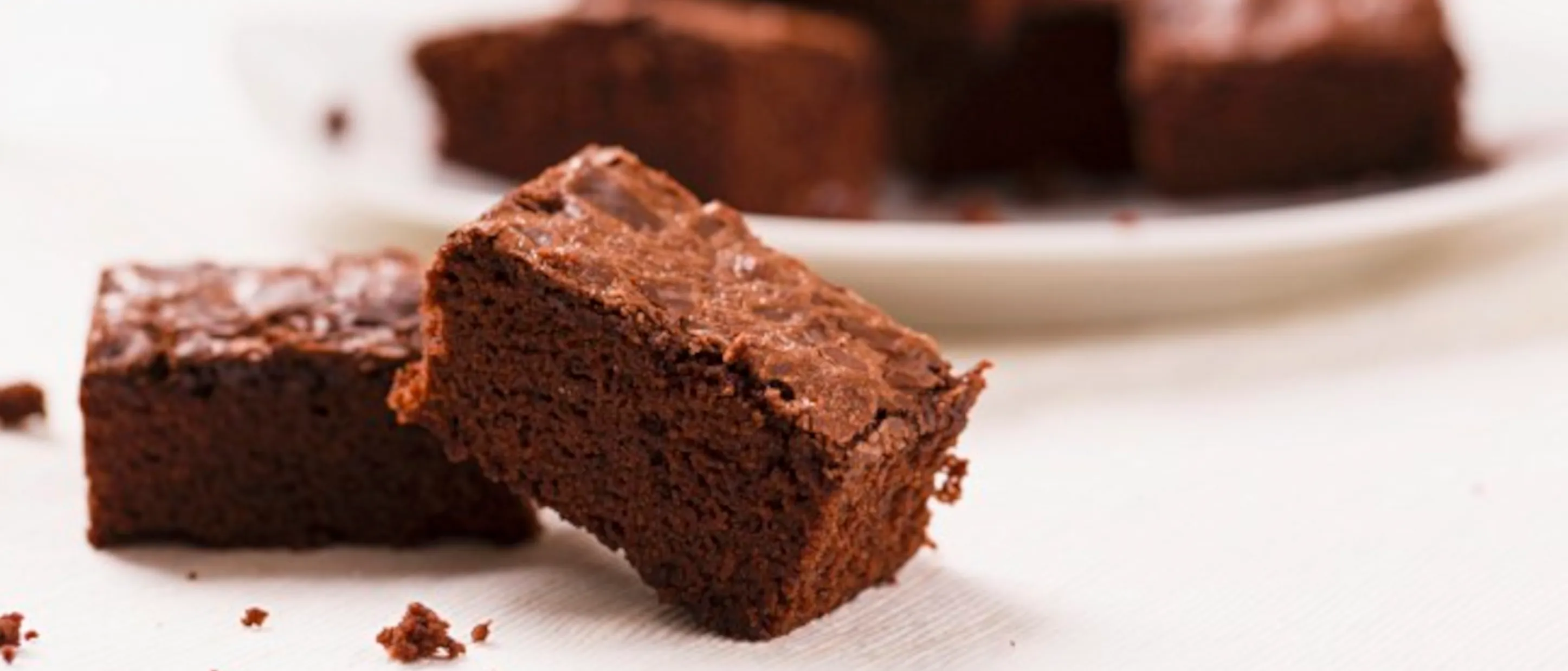 Nahaufnahme von Schokoladen-Brownies, mit Krümeln auf einem weißen Tisch